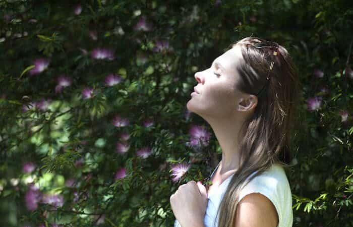 Woman in a forest breathing in flower scents.