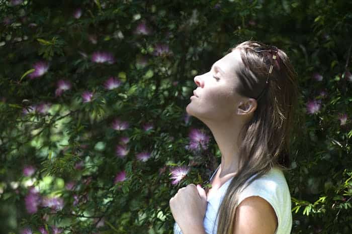 Woman in a forest breathing in flower scents.