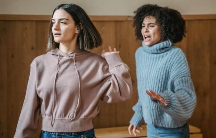 A young woman in a pinkish sweatshirt seems to be showing a challenging behaviour to another woman who looks like she's trying to help her.