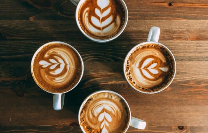 4 cappuccinos on a wooden table