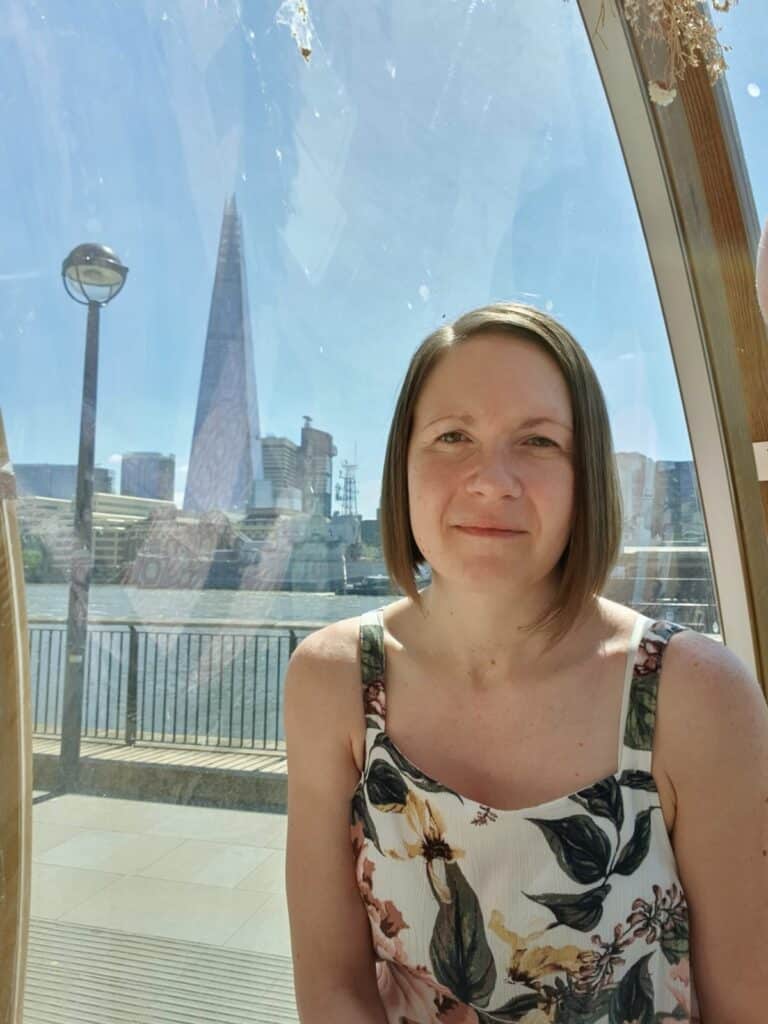 Woman smiling with the Shard in teh distance behind her.