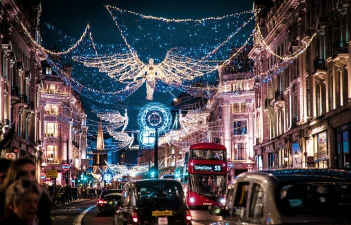 A car-filled London street at night decorated with festive lights.